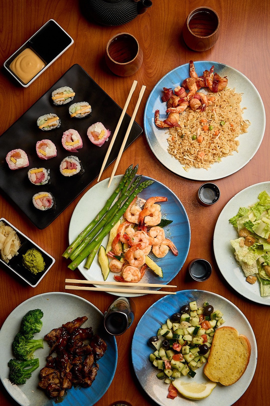 Sushi rolls and shrimp fried rice photographed on a wooden restaurant table